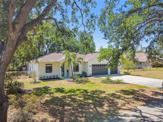 ranch-style home with a garage, stucco siding, driveway, and a front yard