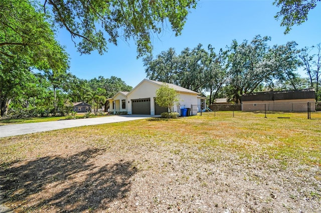 exterior space featuring a garage, a front lawn, fence, and concrete driveway