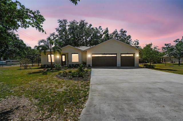 ranch-style home featuring an attached garage, stucco siding, driveway, and a front lawn