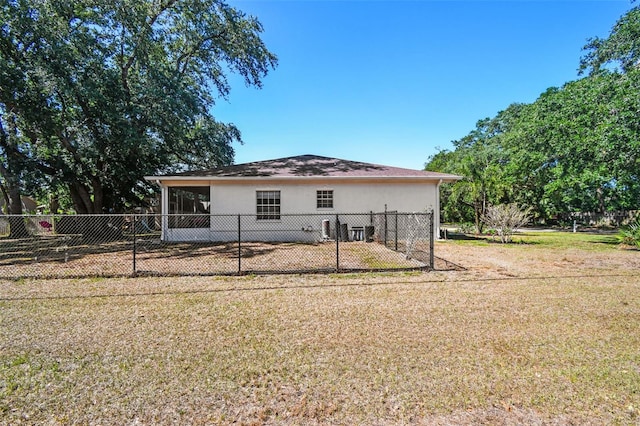 rear view of house featuring a yard, a fenced backyard, and stucco siding