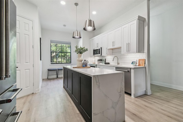kitchen featuring baseboards, recessed lighting, a center island, appliances with stainless steel finishes, and backsplash