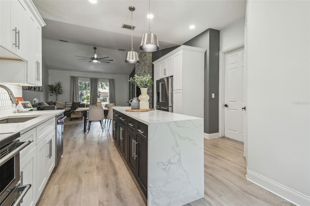 kitchen with a sink, white cabinetry, a kitchen island, and stainless steel appliances