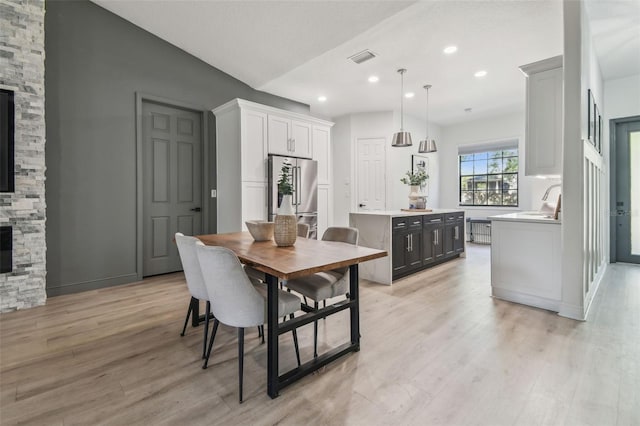 dining area with a fireplace, recessed lighting, visible vents, and light wood-style floors