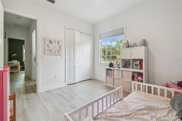 bedroom featuring baseboards, wood finished floors, visible vents, and a closet