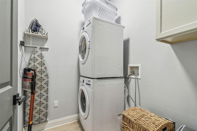 laundry area featuring stacked washing maching and dryer, baseboards, and cabinet space
