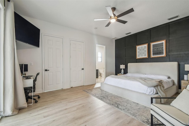 bedroom with ensuite bathroom, light wood finished floors, ceiling fan, and visible vents