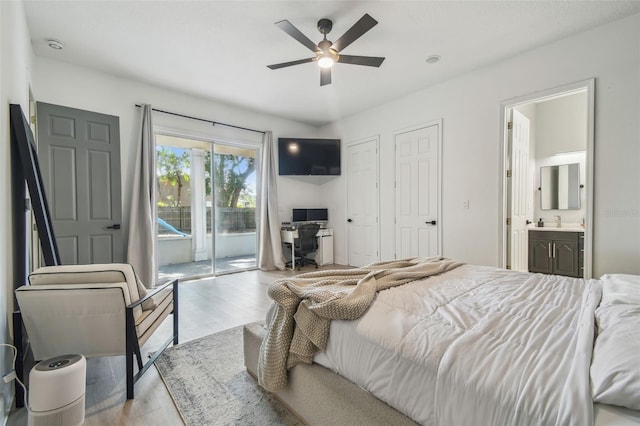 bedroom featuring ceiling fan, wood finished floors, a sink, access to outside, and ensuite bath