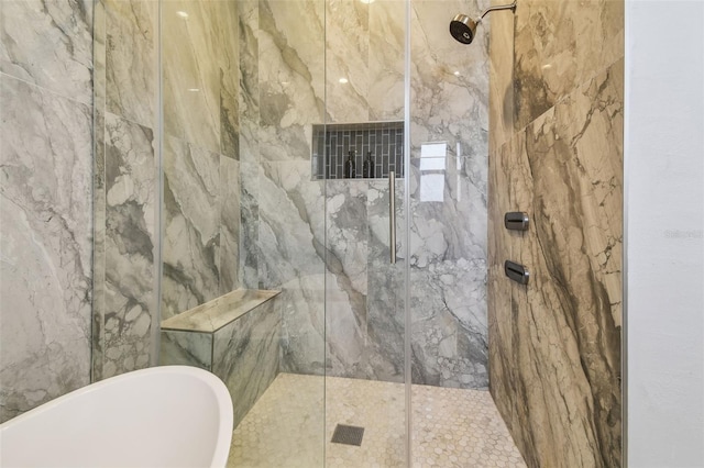 bathroom featuring a freestanding bath and a marble finish shower