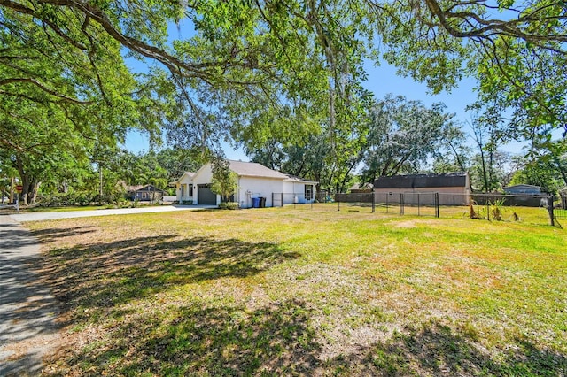view of yard with a garage, fence, and driveway