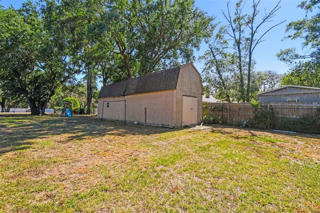 view of yard with a barn, fence, an outbuilding, and a playground