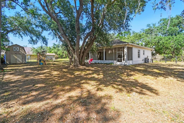 view of yard with a sunroom, fence, an outbuilding, and a storage unit