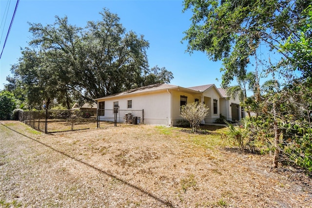 view of side of property featuring fence, a gate, and stucco siding