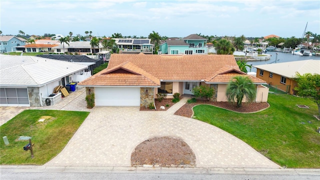 view of front of home featuring an attached garage, a residential view, a tiled roof, a front lawn, and decorative driveway