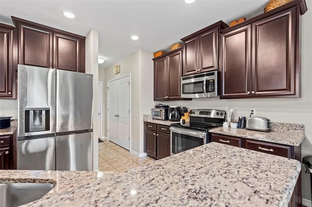 11871 Crestridge Loop, Trinity, FL 34655 - kitchen featuring light stone counters, appliances with stainless steel finishes, and light tile patterned floors