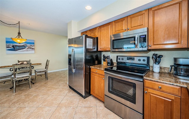 kitchen with dark stone counters, appliances with stainless steel finishes, and brown cabinets