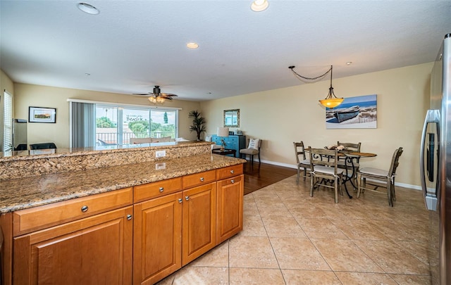 kitchen featuring brown cabinets, light tile patterned floors, baseboards, stainless steel fridge, and recessed lighting