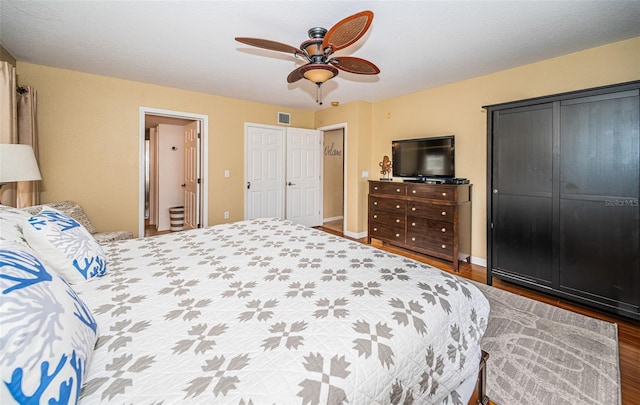 bedroom with a ceiling fan, baseboards, visible vents, and wood finished floors