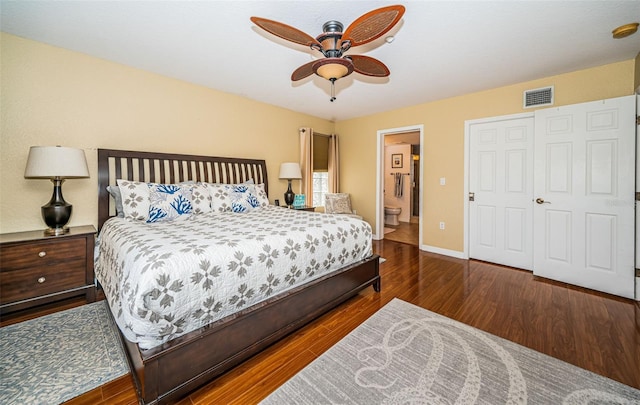 bedroom featuring a ceiling fan, visible vents, wood finished floors, baseboards, and ensuite bathroom