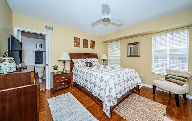bedroom featuring a ceiling fan, visible vents, dark wood finished floors, baseboards, and ensuite bathroom