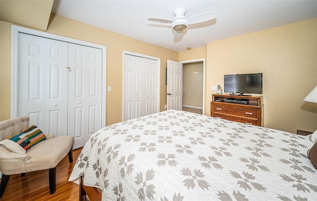bedroom with a ceiling fan, multiple closets, and wood finished floors