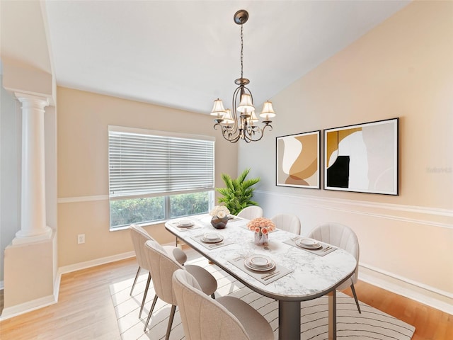 dining room featuring a notable chandelier, baseboards, lofted ceiling, ornate columns, and light wood-style flooring