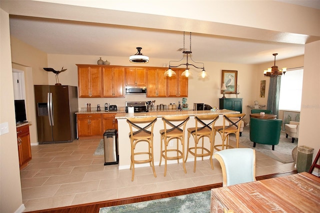 kitchen featuring a kitchen bar, brown cabinets, light countertops, a chandelier, and stainless steel appliances