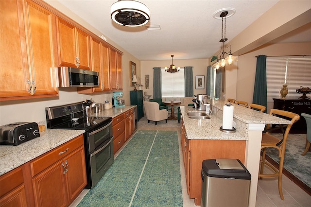 kitchen with brown cabinetry, appliances with stainless steel finishes, a breakfast bar, and a sink