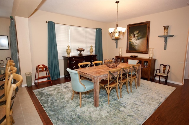 dining space with an inviting chandelier, baseboards, and wood finished floors