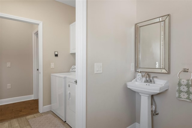 bathroom featuring separate washer and dryer, baseboards, wood finished floors, and a sink