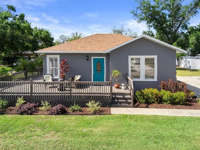 bungalow-style home with stucco siding, a wooden deck, and a shingled roof