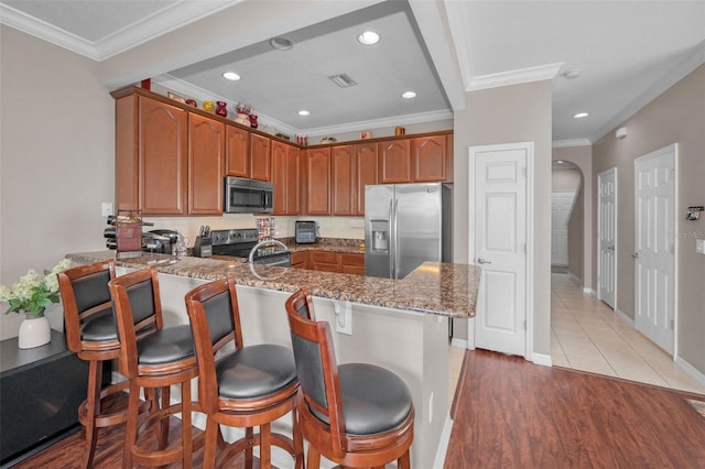 6902 47th Ln N, Pinellas Park, FL 33781 - kitchen with visible vents, ornamental molding, a peninsula, stone counters, and stainless steel appliances