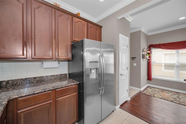 6902 47th Ln N, Pinellas Park, FL 33781 - kitchen featuring stainless steel fridge with ice dispenser, ornamental molding, light tile patterned flooring, dark stone counters, and tasteful backsplash