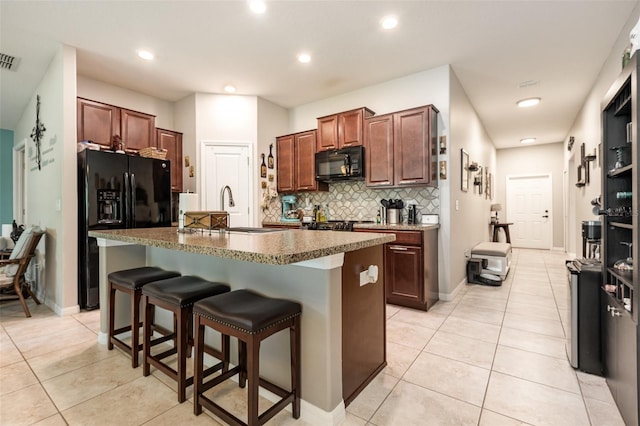 kitchen with light tile patterned floors, decorative backsplash, black appliances, and a sink