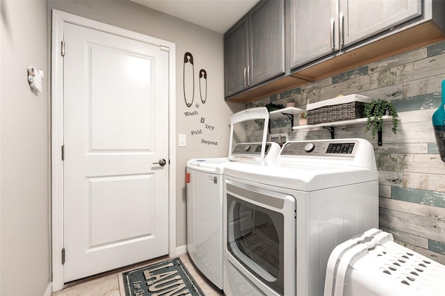 laundry area with baseboards, washer and dryer, light tile patterned floors, and cabinet space