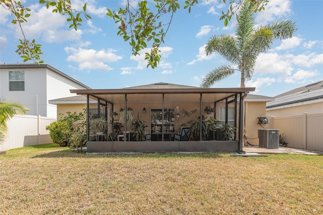 back of property with fence, stucco siding, a lawn, central AC unit, and a sunroom