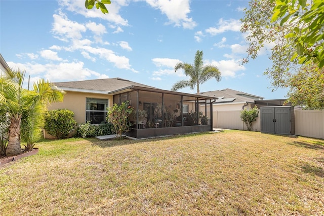 back of property with a yard, a sunroom, a storage shed, and a fenced backyard