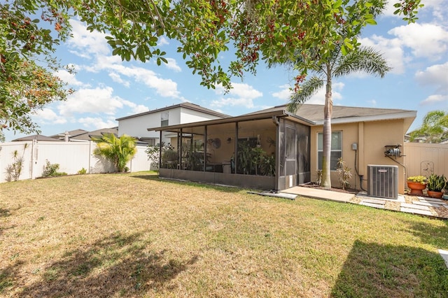 rear view of house featuring a yard, central air condition unit, a sunroom, and a fenced backyard