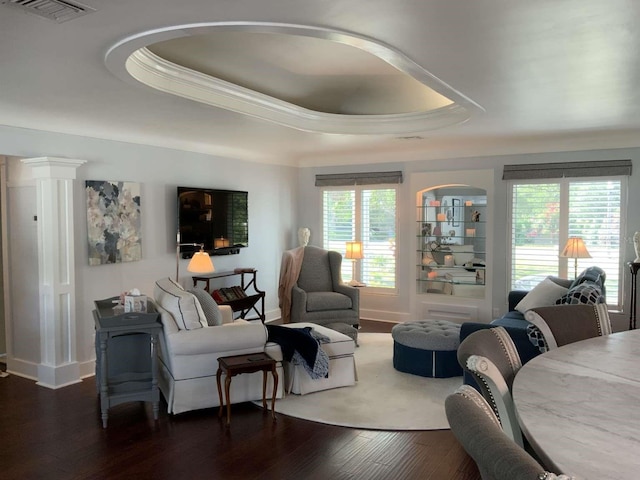 living area featuring crown molding, visible vents, baseboards, dark wood-type flooring, and a tray ceiling