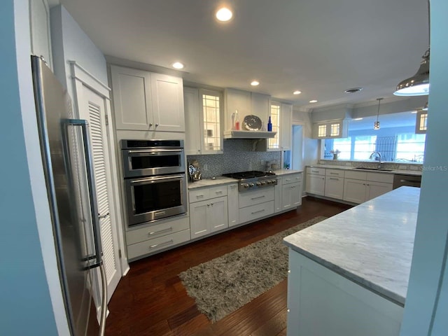 kitchen with a sink, appliances with stainless steel finishes, tasteful backsplash, and white cabinets