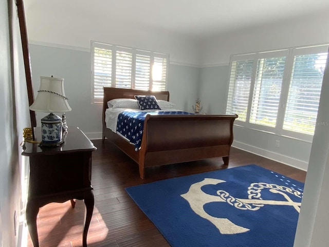 bedroom with baseboards, multiple windows, and wood finished floors