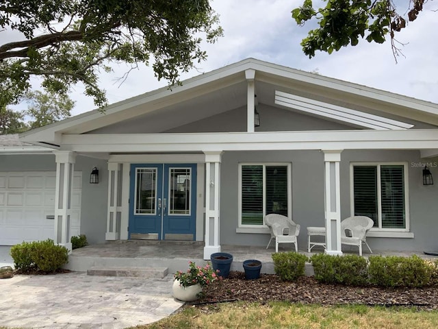 209 Rosery Rd, Belleair, FL 33756 - property entrance with a porch, french doors, an attached garage, and stucco siding