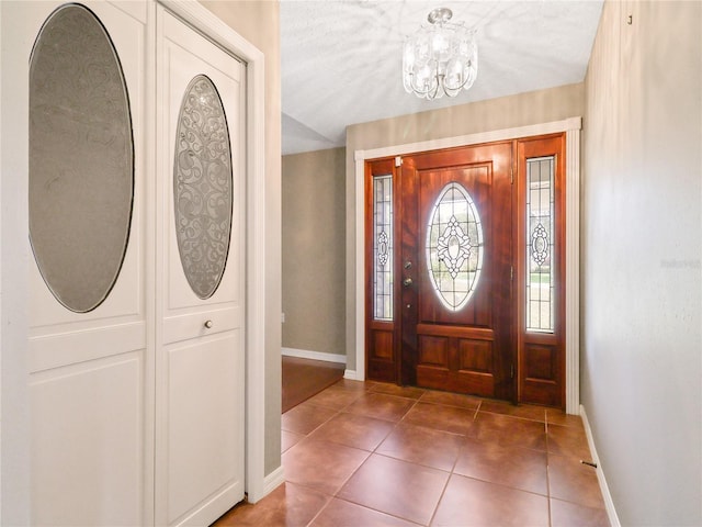 entryway with a chandelier, baseboards, and tile patterned flooring