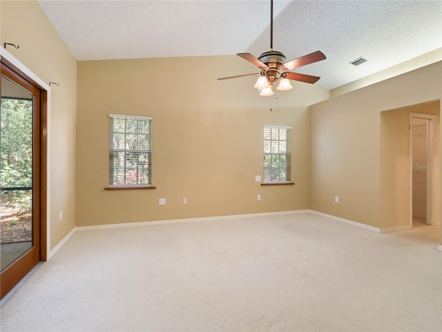 empty room featuring light colored carpet, a textured ceiling, lofted ceiling, and a ceiling fan
