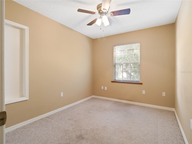 carpeted spare room featuring a textured ceiling, baseboards, and a ceiling fan