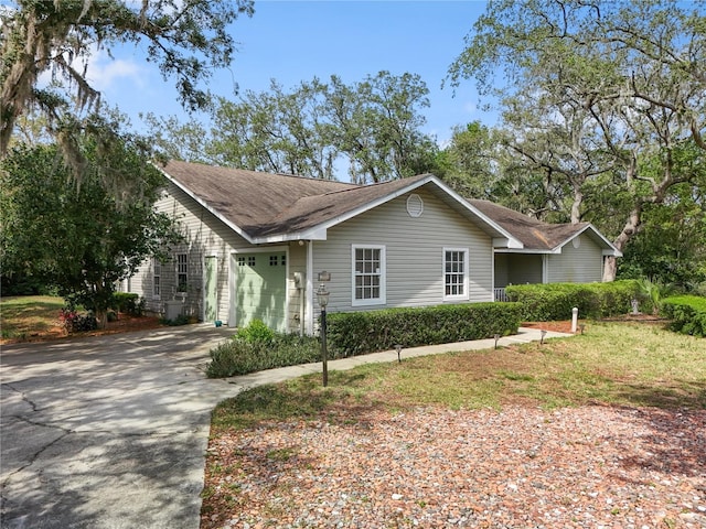 ranch-style house with concrete driveway, a shingled roof, and a garage