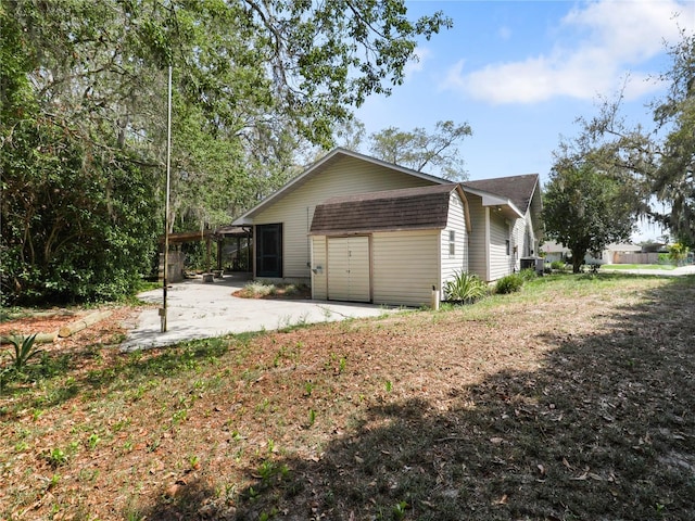 view of property exterior with a patio area, an attached garage, a sunroom, and a shingled roof