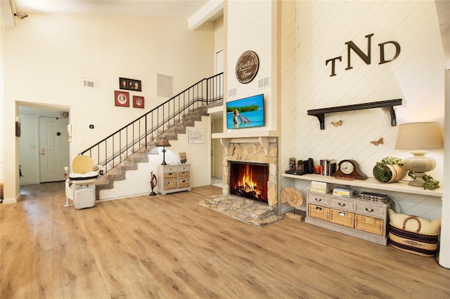 living room featuring high vaulted ceiling, wood finished floors, a fireplace, stairway, and baseboards