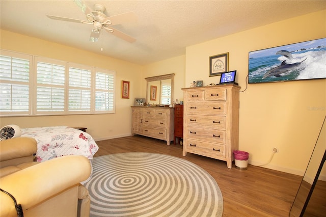 bedroom featuring wood finished floors, baseboards, and a ceiling fan