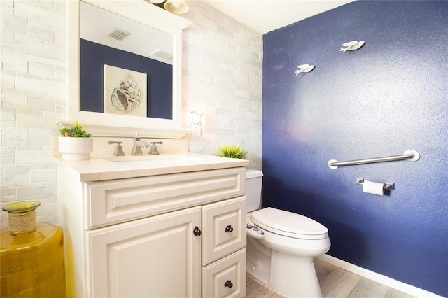 bathroom featuring vanity, toilet, wood finished floors, and tile walls