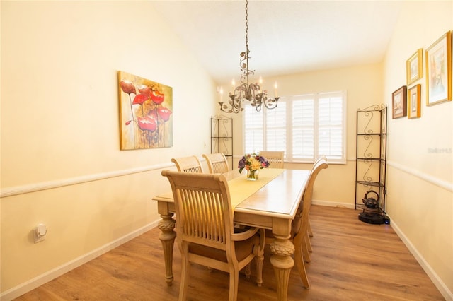 dining room with a chandelier, light wood-type flooring, baseboards, and vaulted ceiling